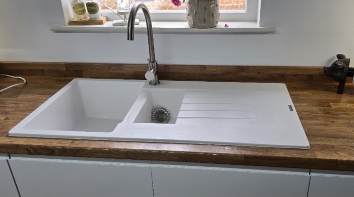 White composite kitchen sink and mixer tap fitted into a solid oak worktop