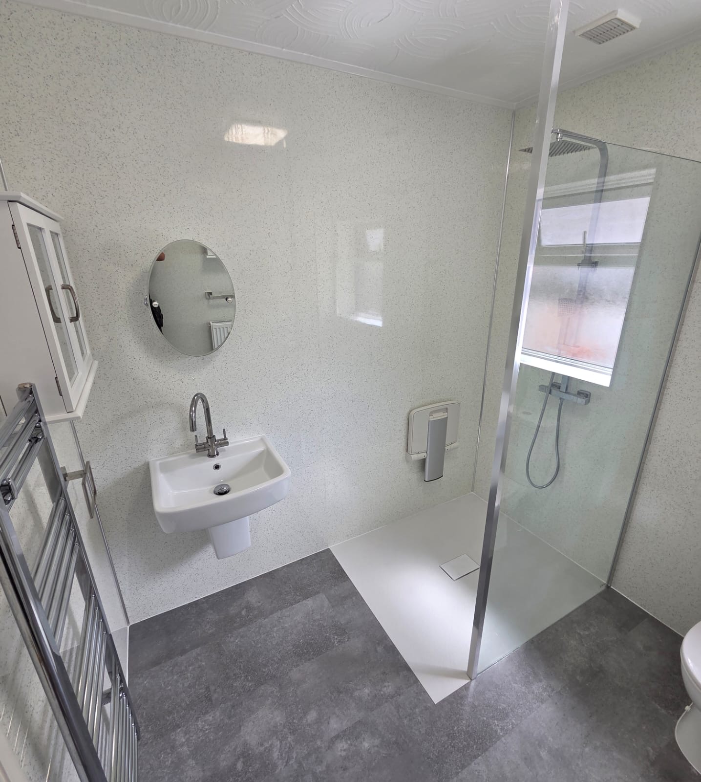White sparkle panelled wet room with level access shower tray and heated towel rail
